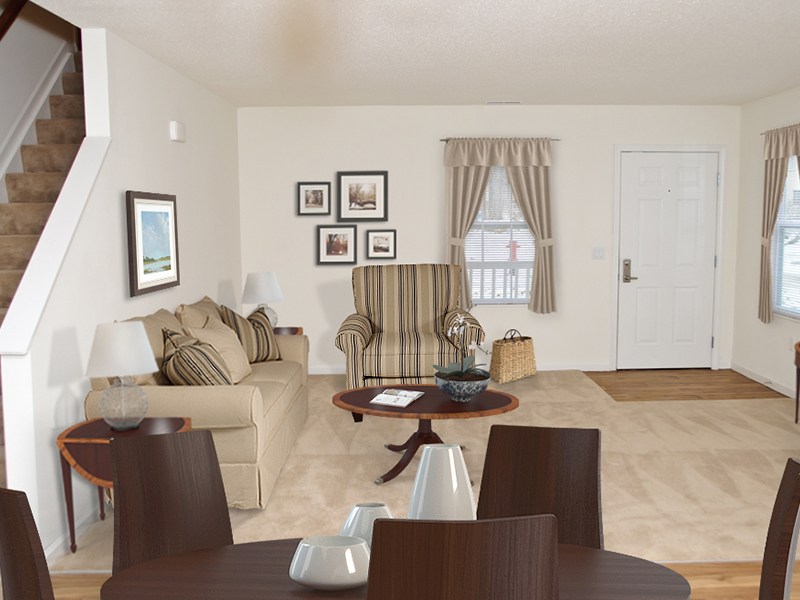 A living room with a brown couch, a coffee table, and a staircase.